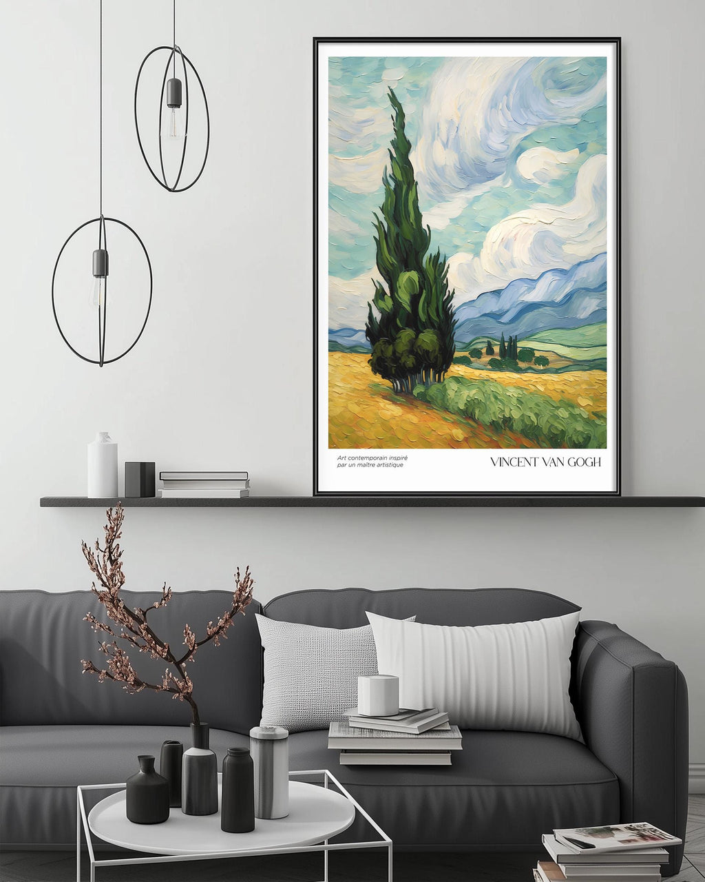 a large painting of a landscape with a tall tree in the foreground, hanging on a wall above a gray couch with a coffee table in front of it. The painting is framed and appears to be a reproduction of Vincent Van Gogh's "Sunflowers".