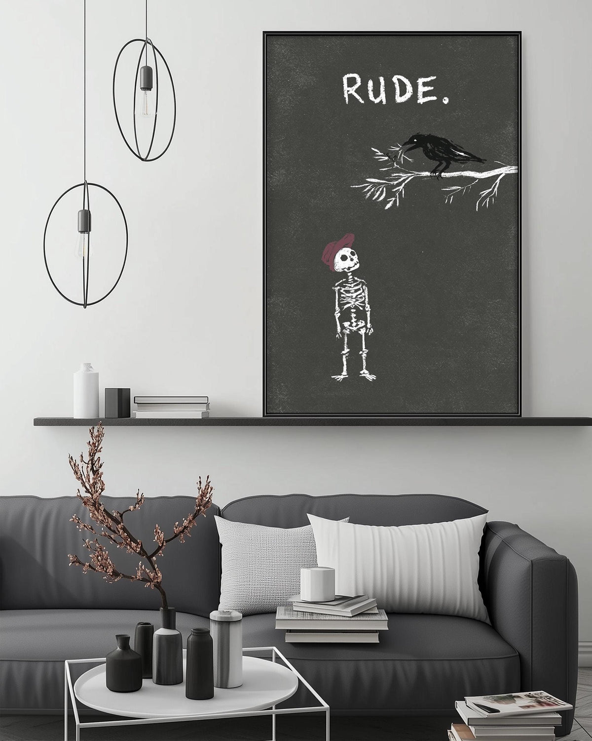 a living room with a gray sofa, a coffee table, and a large black and white poster on the wall. The poster depicts a skeleton wearing a red hat and a bird, with the word "Rude" written above the skeleton.