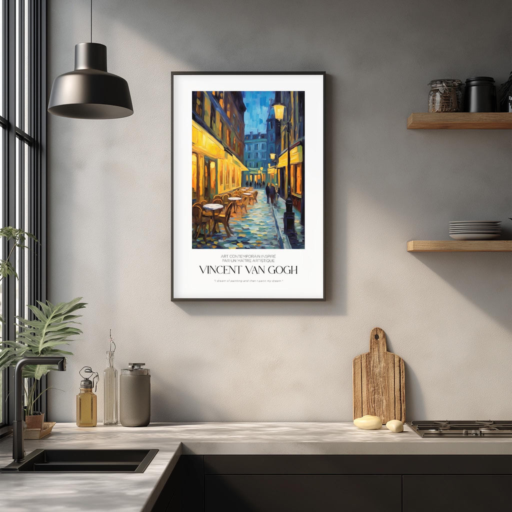 a framed painting of a street scene with a building and a person walking, hanging on a wall above a kitchen counter with various kitchen items and decor.
