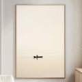 a serene living room with a large white sofa, a wooden side table, and a framed picture of a boat on a calm body of water.