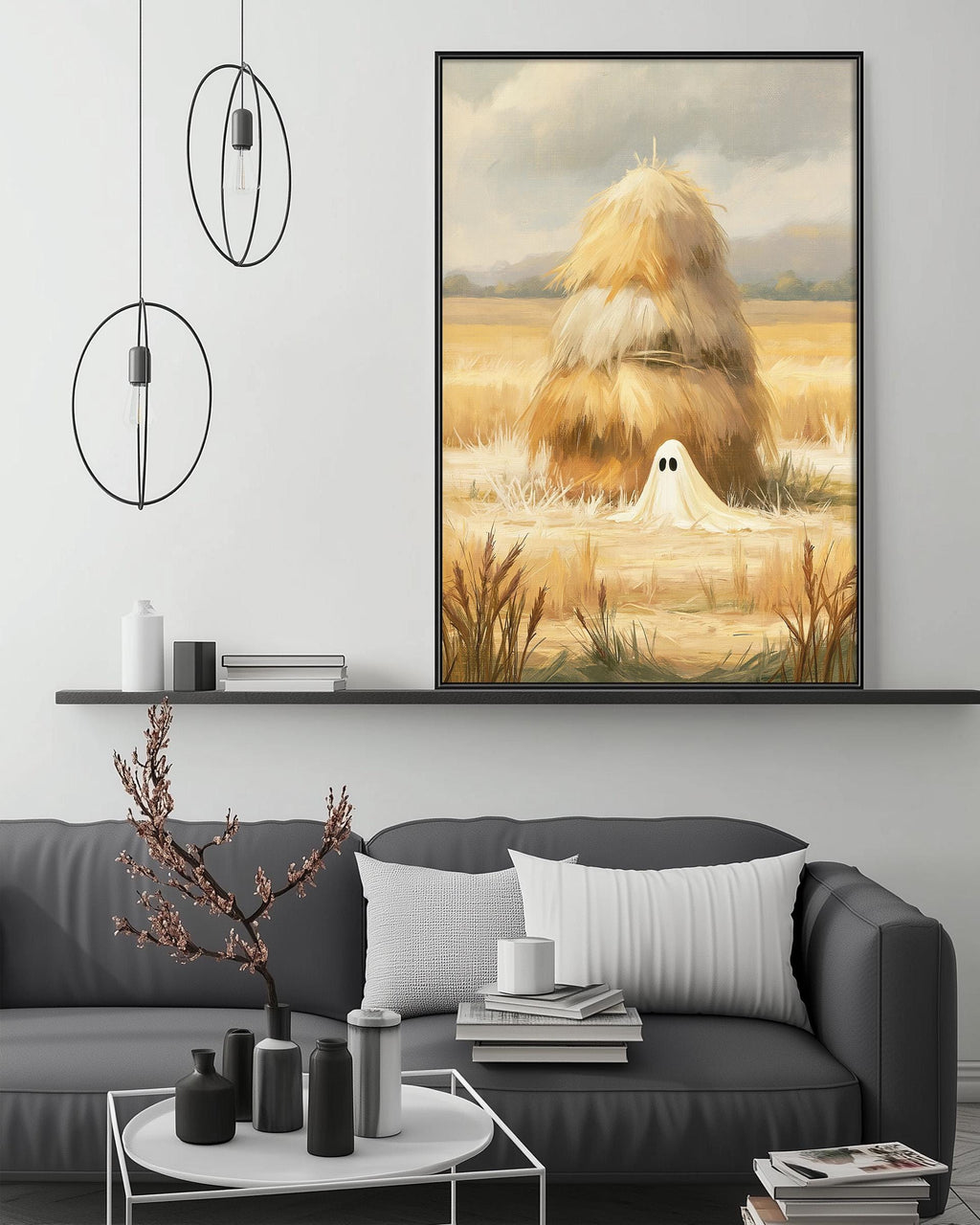 a cozy living room with a gray sofa, a coffee table, and a large framed painting of a field with a hay stack in the background.