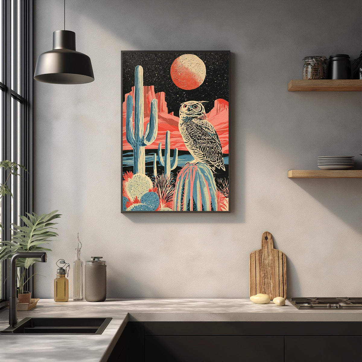 a kitchen counter with a wooden cutting board, a cactus plant, and a potted plant. Above the counter, there is a framed artwork depicting a desert landscape with a large moon and an owl perched on a rock.