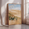 a large framed poster with a serene landscape of wheat fields and a blue sky, accompanied by the text "SLOW LIVING" in the center.