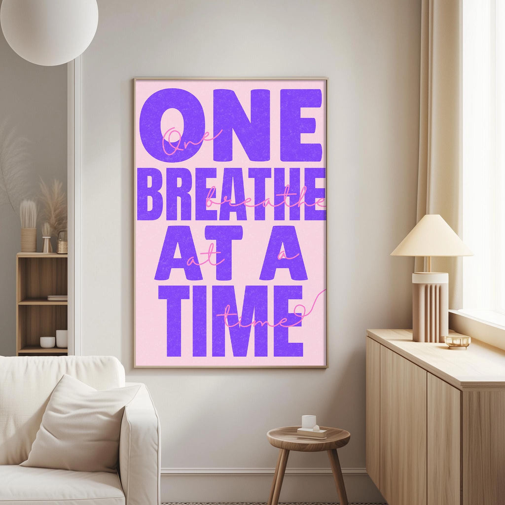 a poster with the text "One breath at a time" in large purple letters on a pink background.