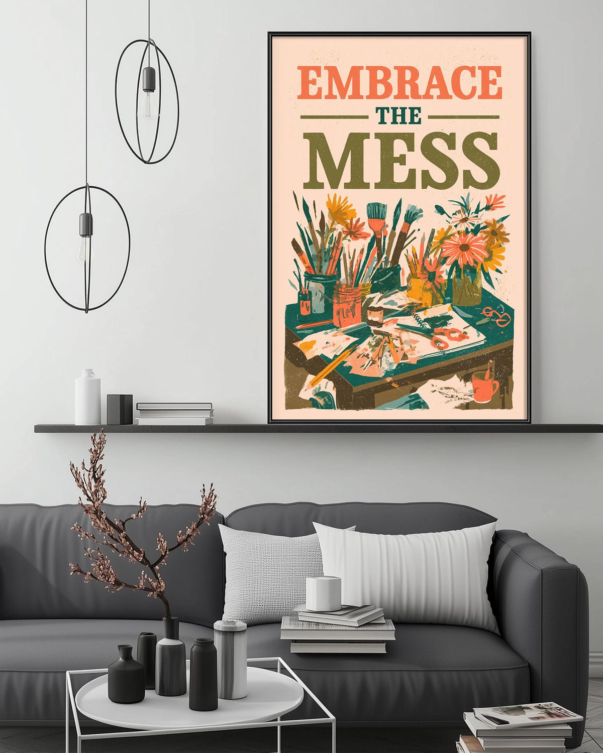 a living room with a gray couch, a coffee table, and a framed poster on the wall. The poster has a colorful illustration of various objects, including flowers, books, and a desk, along with the text "Embrace the mess".