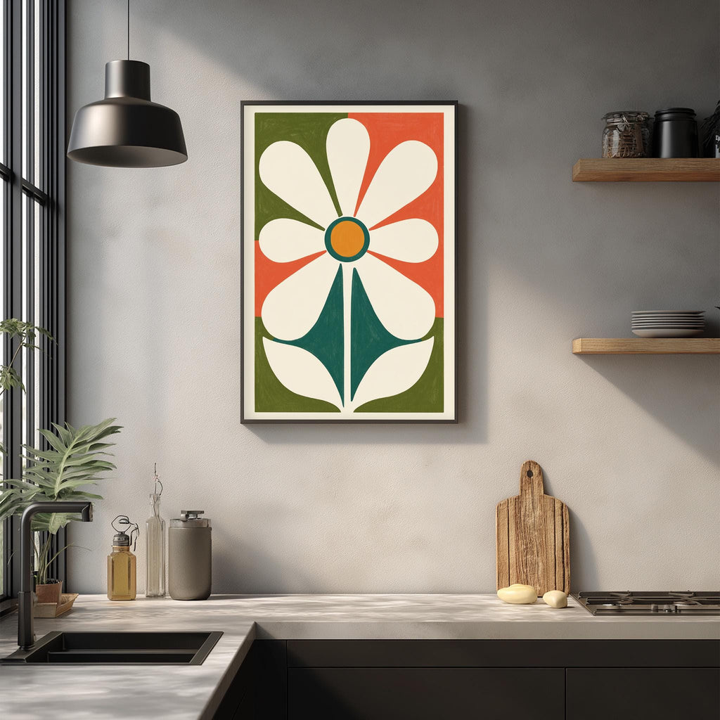 a kitchen counter with a framed abstract flower design hanging on the wall above it. The counter has various kitchen items, such as a cutting board, a knife, and a bottle, as well as a potted plant.