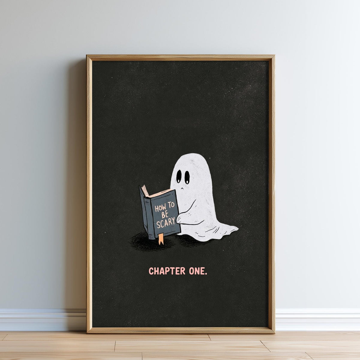 A framed illustration of a ghost reading a book titled "How to Be Scary" against a black background.