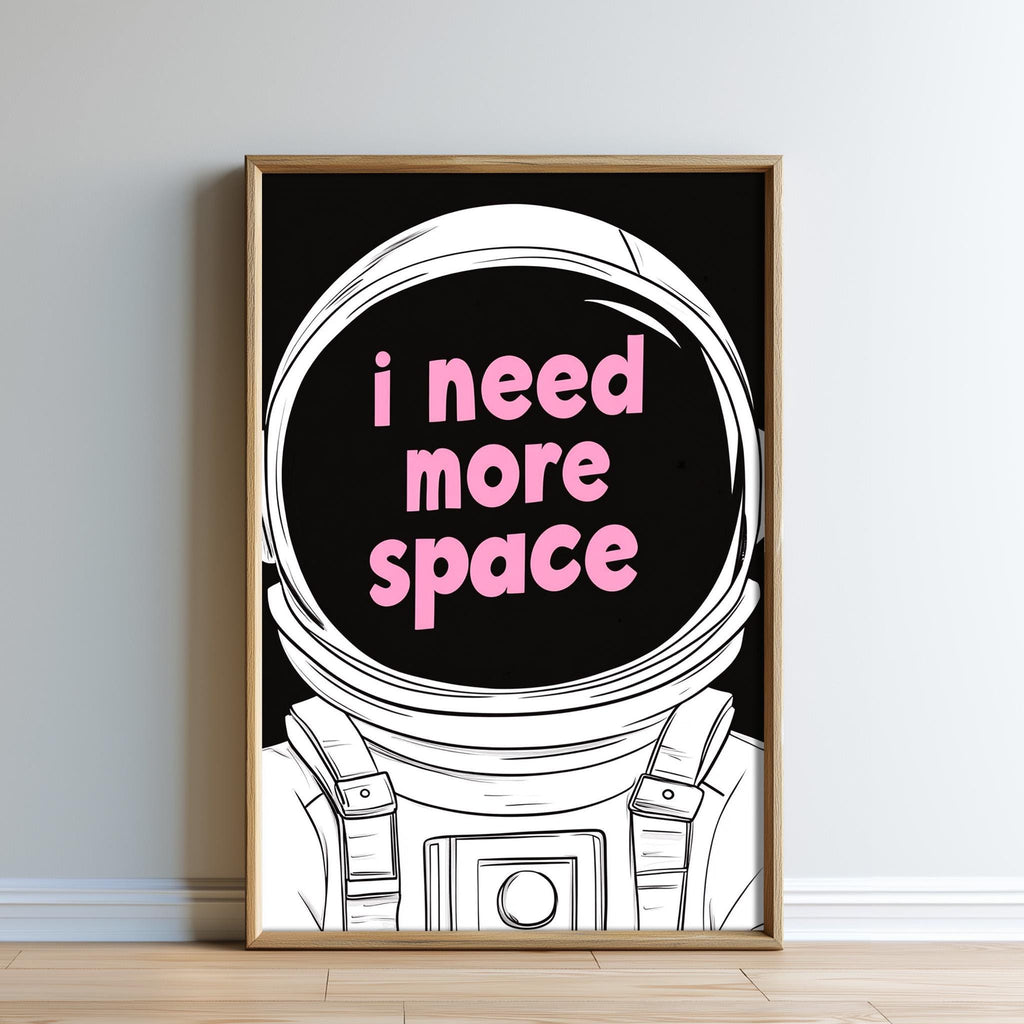 a framed poster with a space-themed illustration and the text "I need more space" in pink letters.