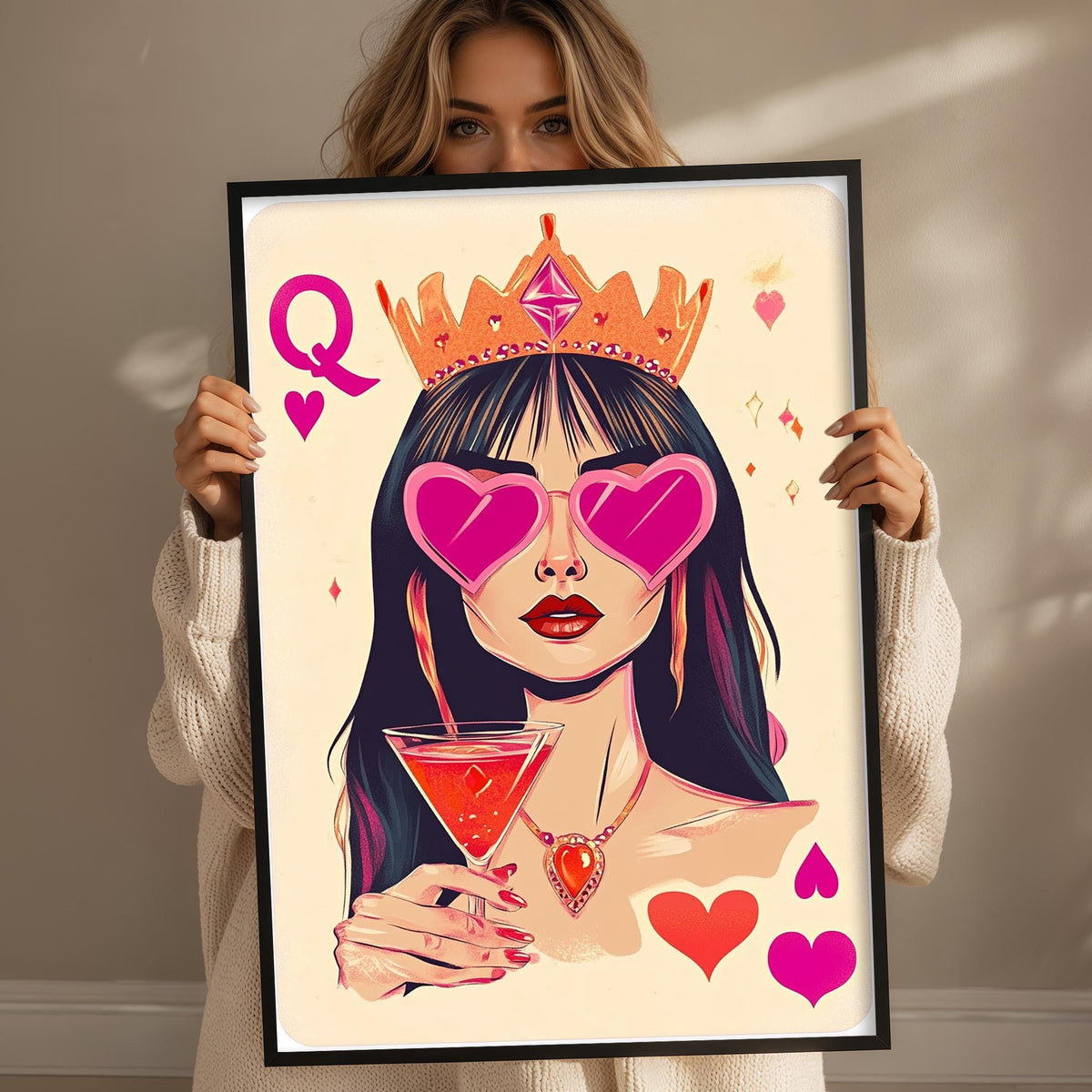 A woman holding a framed illustration of a woman wearing a crown, sunglasses, and holding a drink.