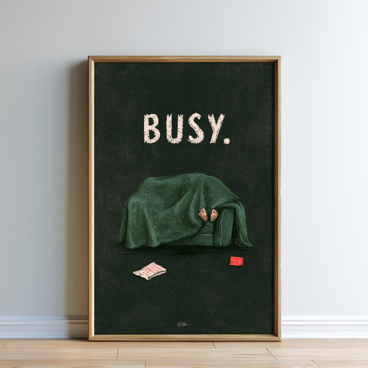 The image is a framed poster with a dark green background and a person sitting on a couch covered with a green blanket. The word "BUSY" is written in white text above the person.