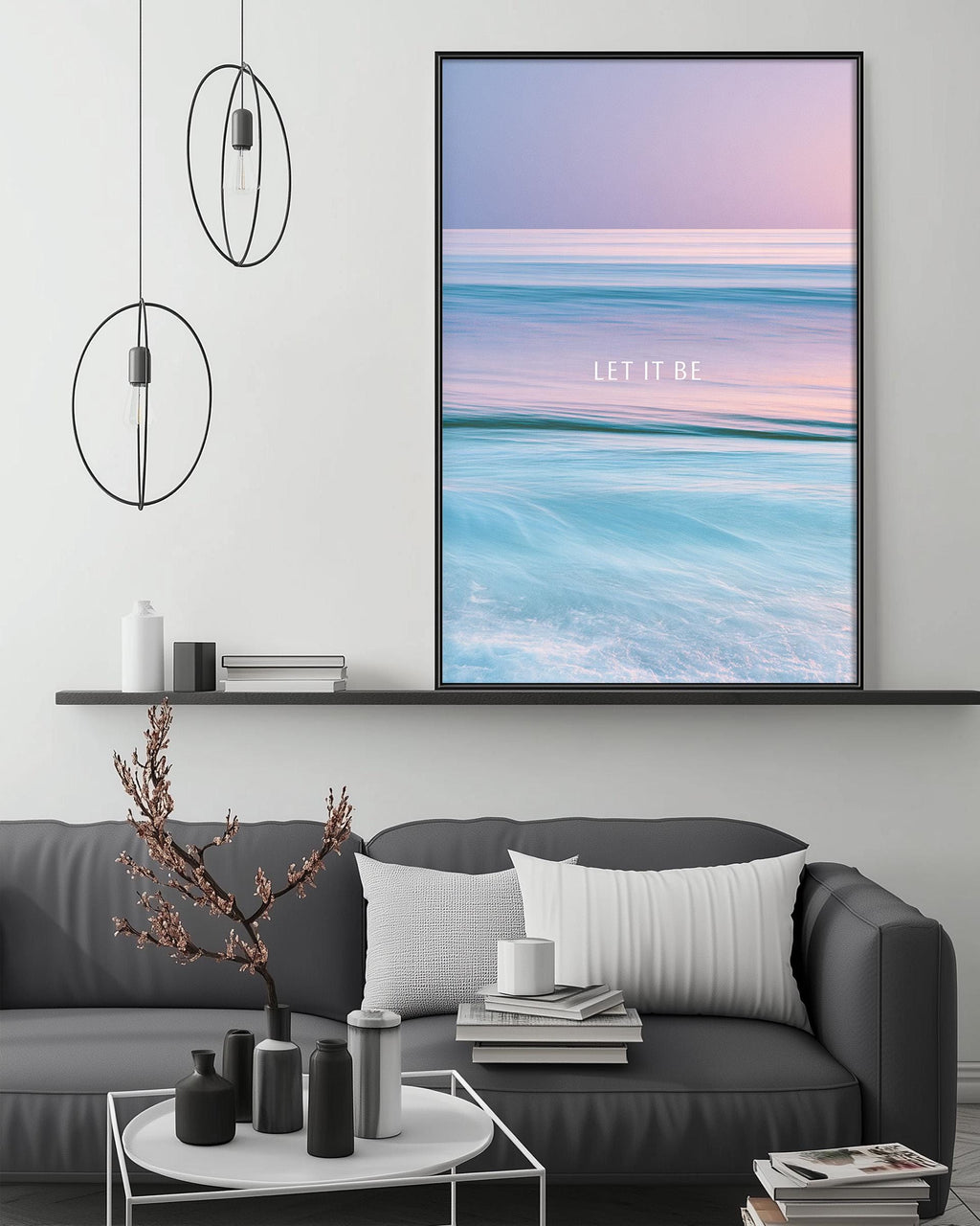 a modern living room with a gray sofa, a coffee table, and a large framed poster of a seascape with the text "LET IT BE" displayed on the wall above the sofa.