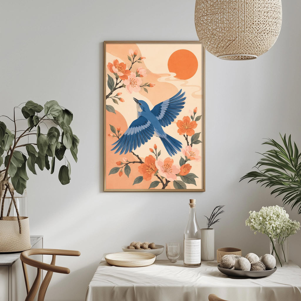 a dining table with a white tablecloth, a bowl of fruit, a bottle, and a vase with flowers. Above the table, there is a framed illustration of a blue bird in flight, surrounded by orange flowers and a large orange sun.