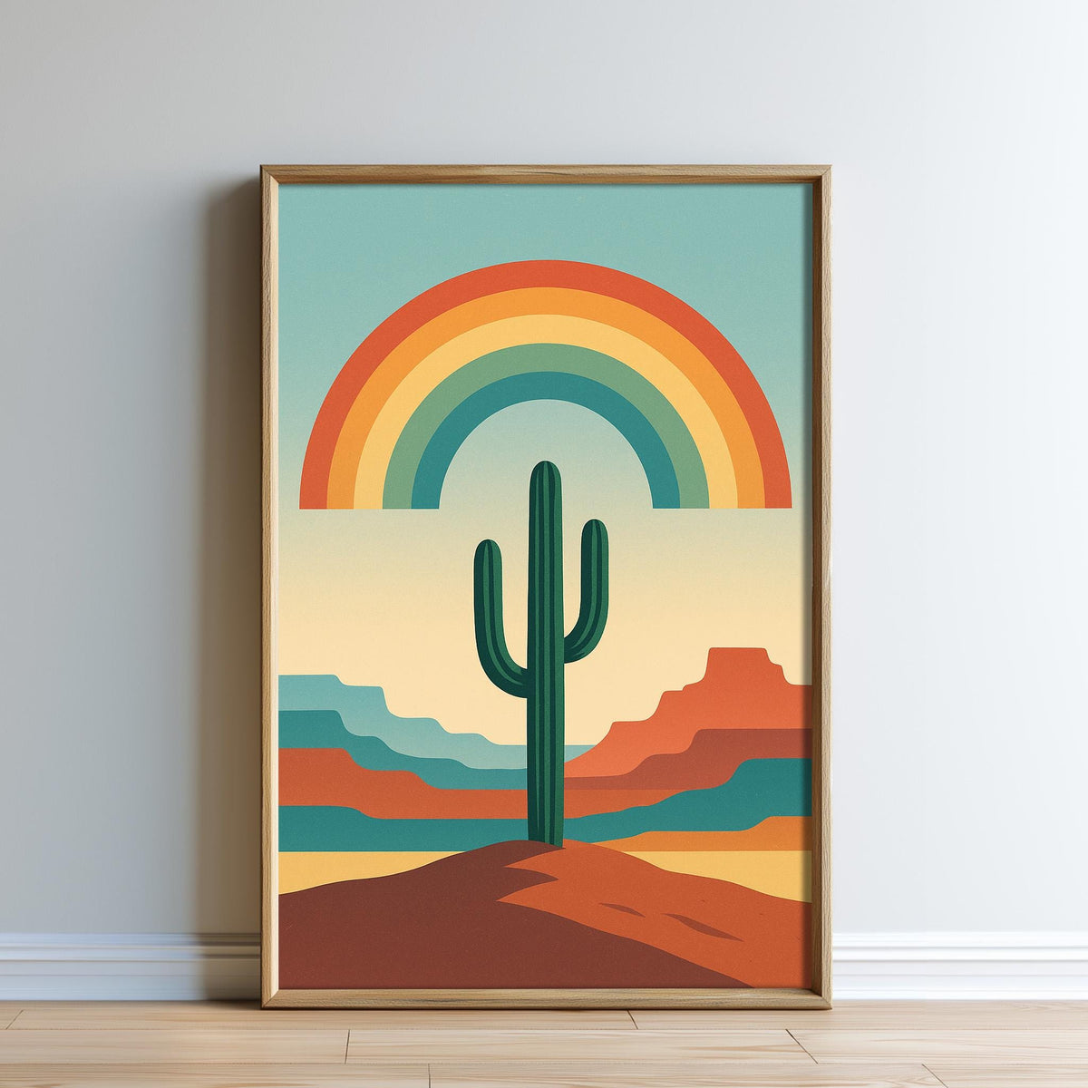 The image is a framed poster depicting a desert landscape with a cactus in the foreground and a rainbow arching across the sky above.