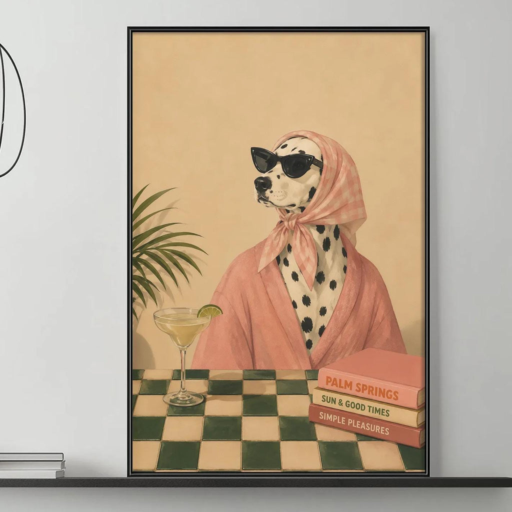 a large framed painting of a Dalmatian dog wearing a pink robe and sunglasses, sitting at a table with a drink and books, in a modern living room setting with a gray sofa, a coffee table, and a potted plant.