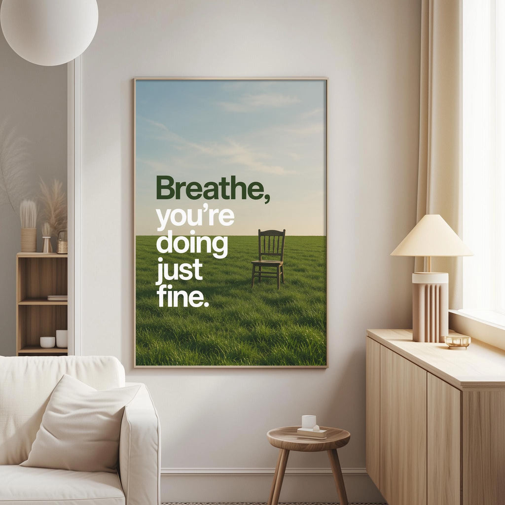 a large framed poster with a serene landscape of a grassy field and a solitary chair, accompanied by the text "Breathe, you're doing just fine."