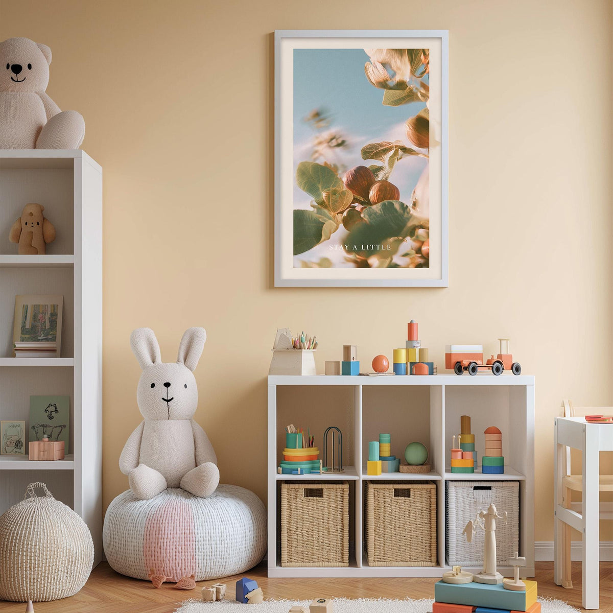A cozy and colorful children's bedroom with a white bookshelf, a plush rabbit, and a toy train set. The walls are painted a light peach color, and there is a framed picture of flowers hanging above the bookshelf.