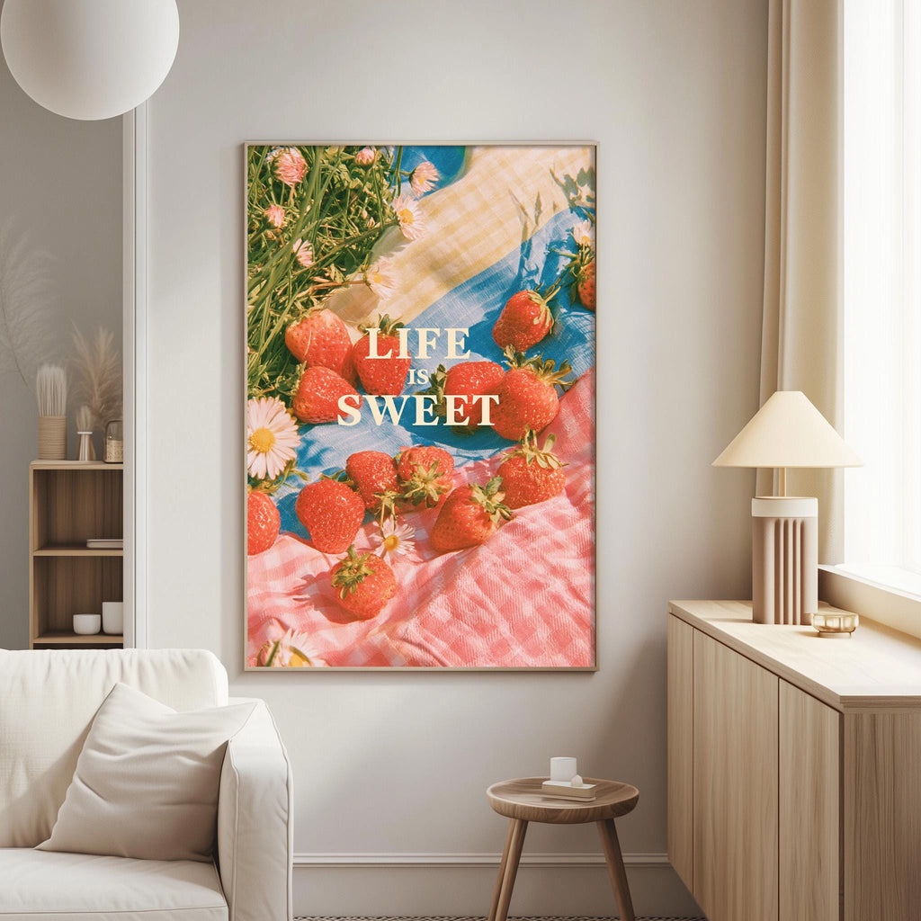 a large framed poster with a vibrant image of strawberries on a pink and blue background, hanging on a wall in a living room.