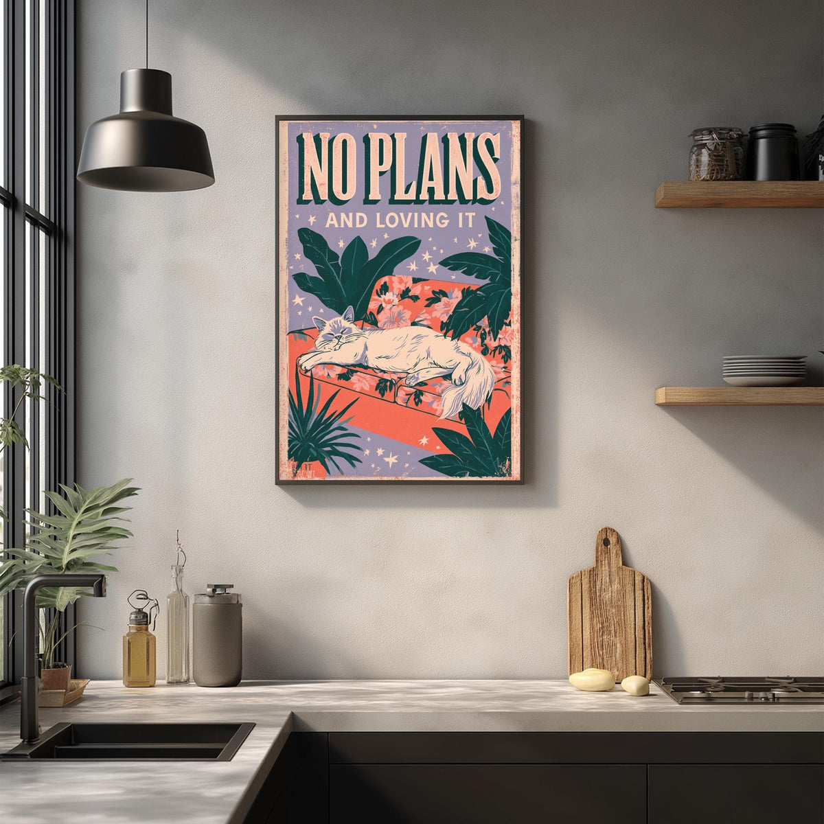 a kitchen counter with various items such as a cutting board, a soap dispenser, and a plant. Above the counter, there is a framed poster with the text "NO PLANS AND LOVING IT" and an illustration of a cat.