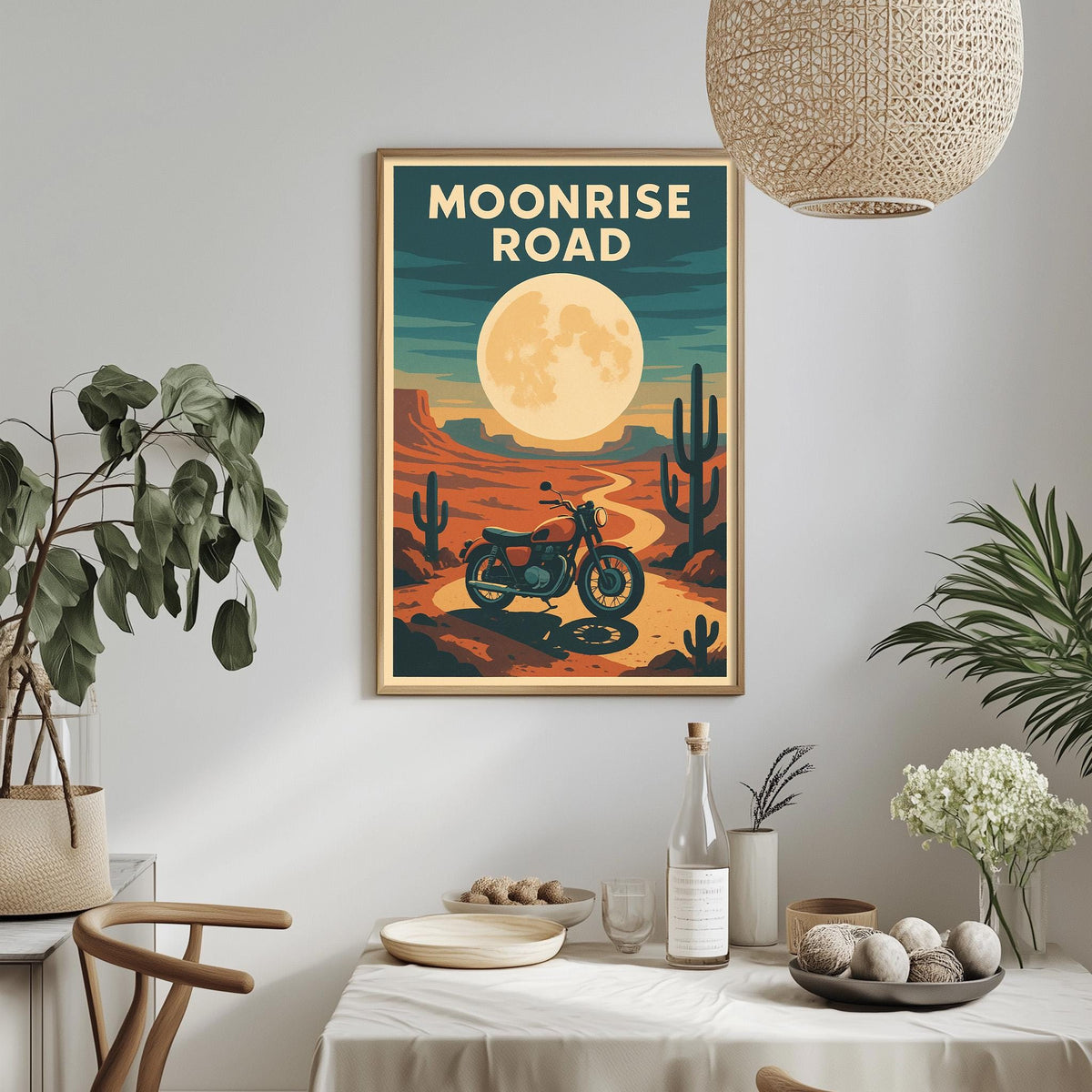 a framed poster of a desert landscape with a motorcycle in the foreground, hanging on a wall above a dining table with various items on it.
