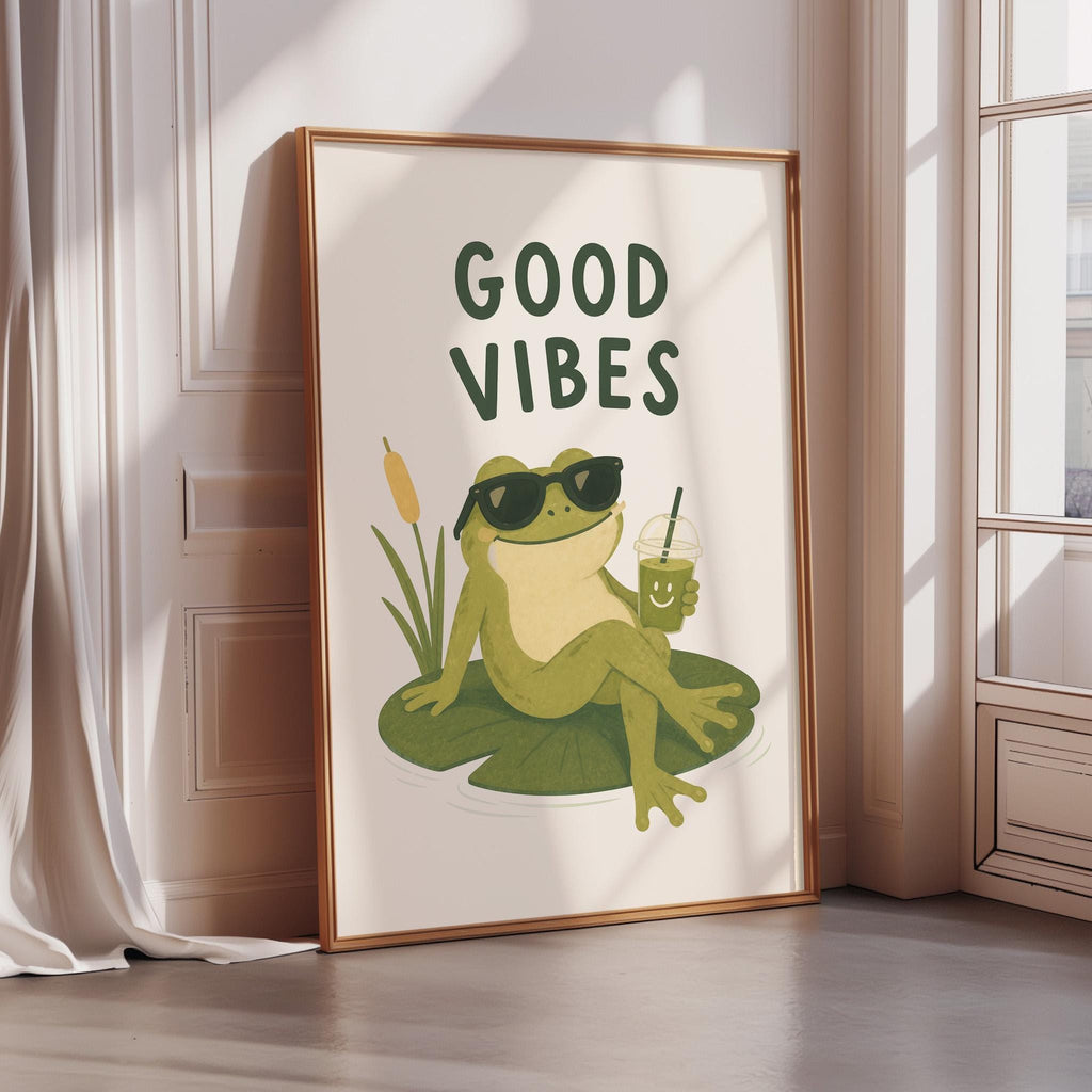 A framed poster with a cartoon frog sitting on a lily pad, wearing sunglasses and holding a drink, with the text "GOOD VIBES" above the image.