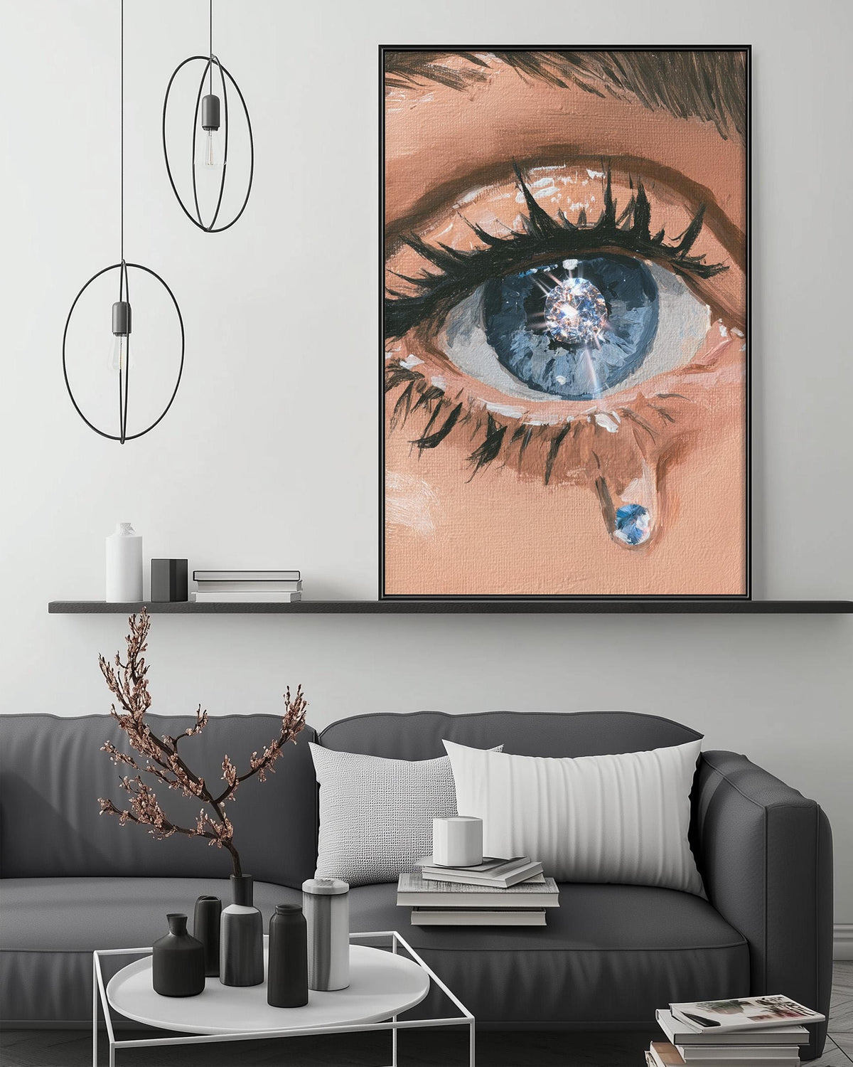 a large painting of a human eye with a tear, hanging on a wall above a gray couch with a coffee table in front of it.