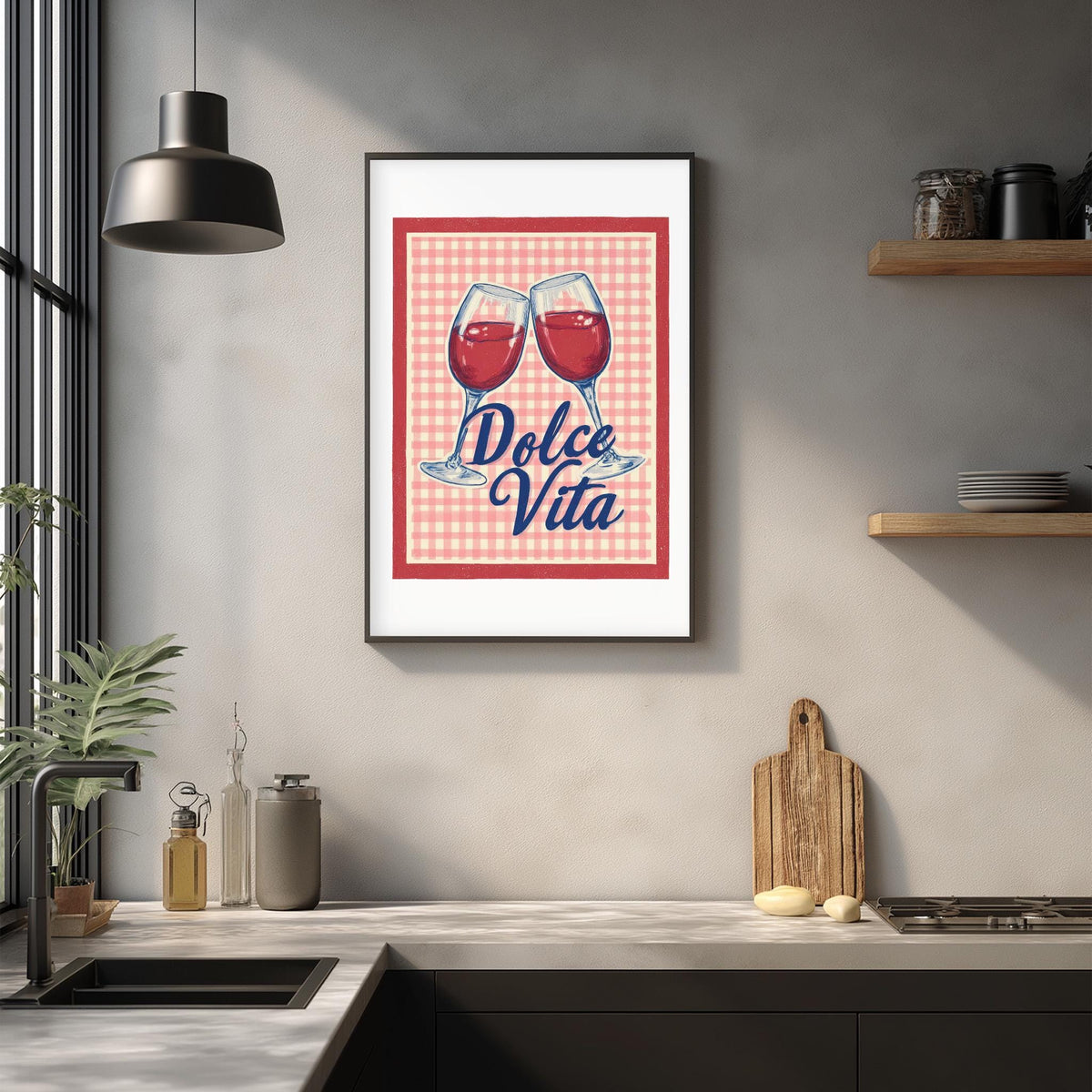 a framed poster with the text "Dolce Vita" hanging on a wall above a kitchen counter with various kitchen items such as a cutting board, a bottle, and a bowl.