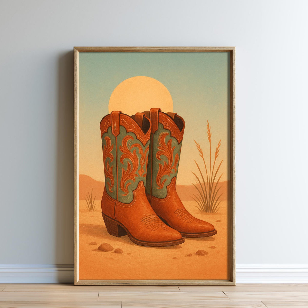A framed painting depicting a pair of brown cowboy boots against a desert landscape with a large sun in the background.