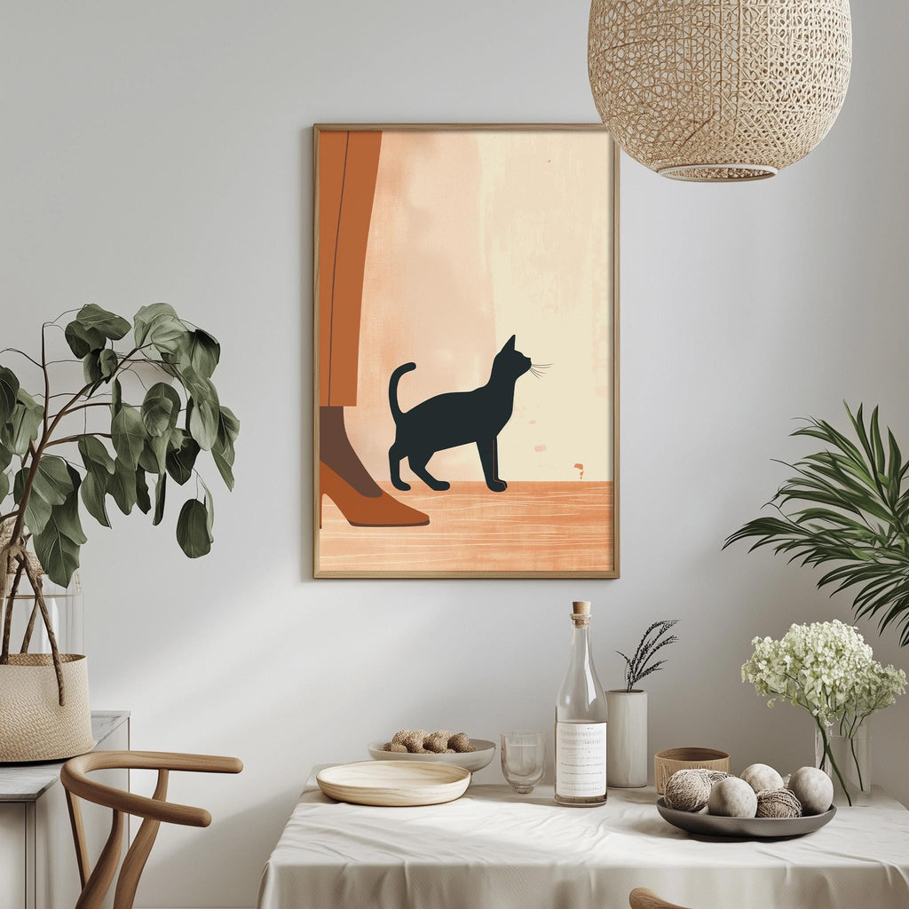a dining table with a white tablecloth, a bowl of fruit, a bottle, and a vase with flowers. Above the table, there is a framed illustration of a cat and a person, and a hanging light fixture.