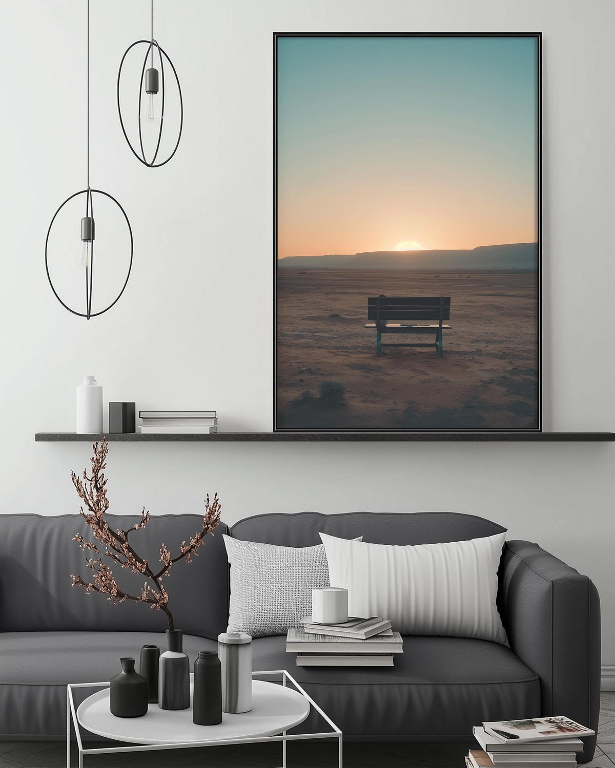 a living room with a gray sofa, a coffee table, and a large framed picture of a bench in the sand with a sunset in the background.