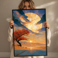 A woman holds up a framed painting depicting a serene landscape with a tree, a sunset, and a body of water.
