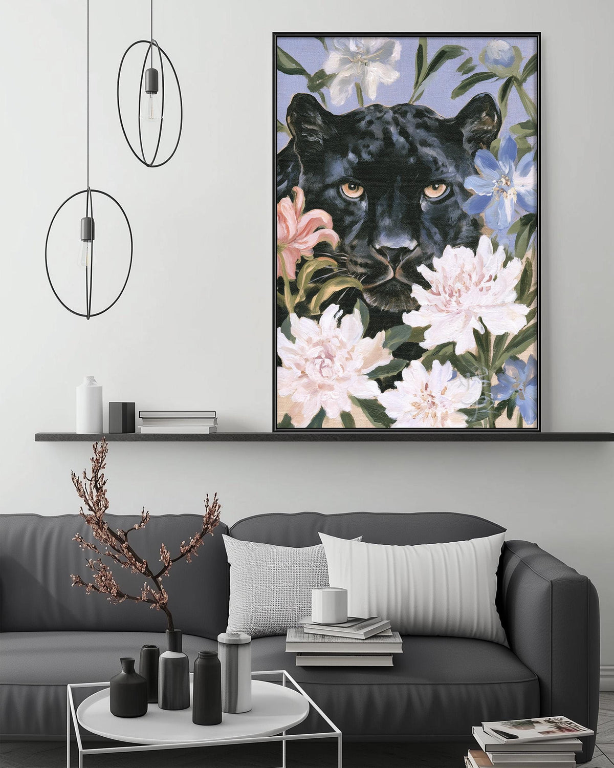 a large framed painting of a black panther surrounded by flowers, hanging on a wall above a gray couch with a coffee table in front of it.