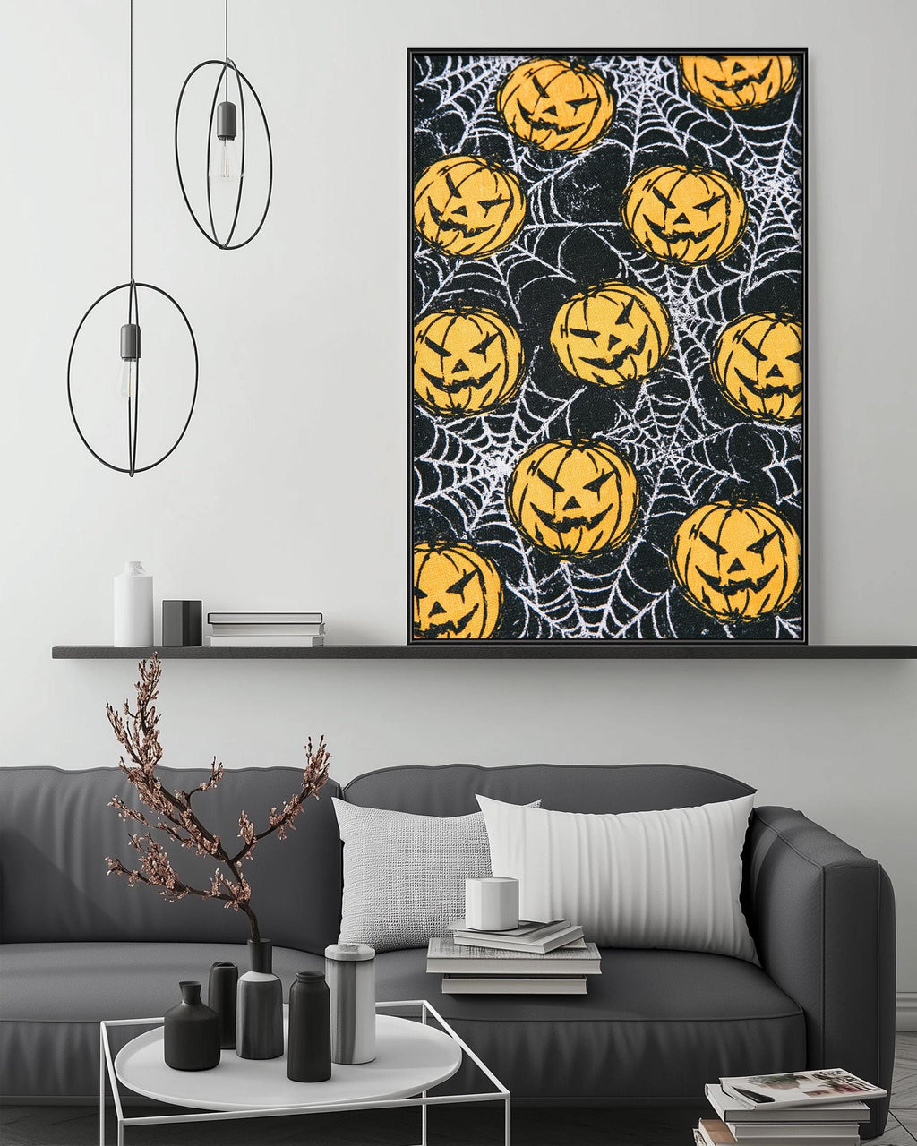 a living room with a gray sofa, a coffee table, and a large framed poster of a Halloween-themed design with jack-o-lanterns and a spider web pattern.