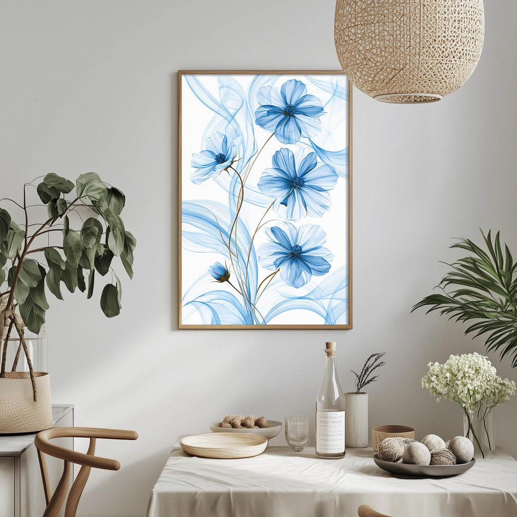 a dining table with a white tablecloth, a bowl of fruit, a bottle, and a vase with flowers. Above the table, there is a framed picture of blue flowers hanging on the wall.