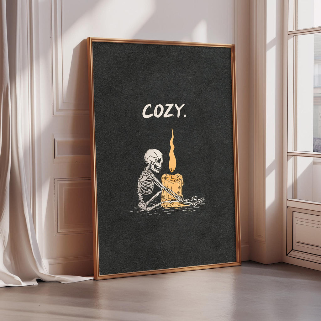A framed poster with a skeleton holding a lit candle, accompanied by the word "COZY" in white text.