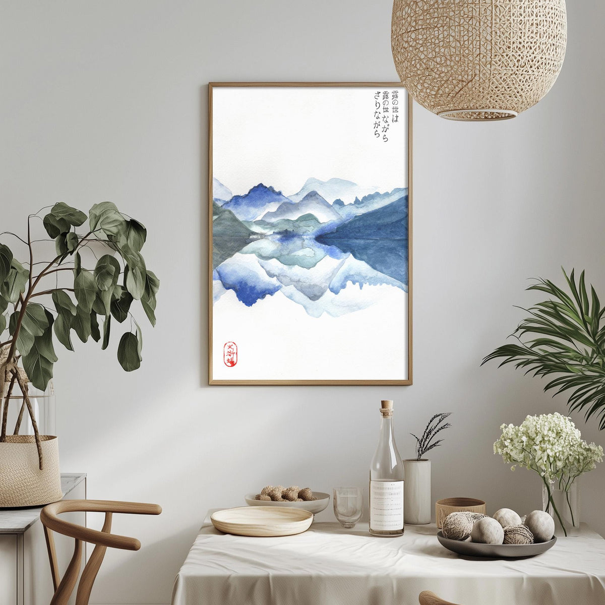a serene indoor setting with a framed watercolor painting of a mountain landscape hanging on the wall. The painting is surrounded by various decorative elements, including potted plants, a vase, and a bowl of fruit. The dining table is set with plates, bowls, and a bottle, creating a cozy and inviting atmosphere.