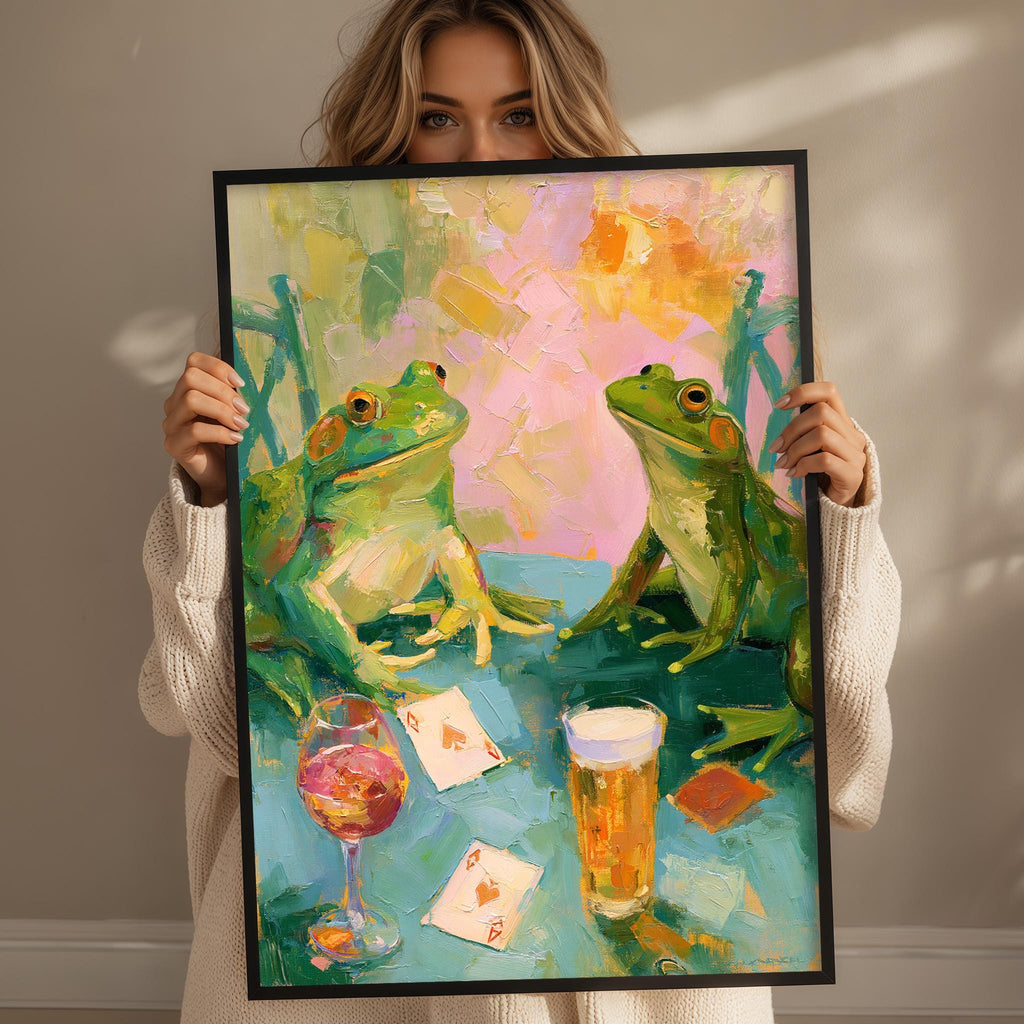 A woman holds up a framed painting depicting two green frogs sitting at a table with a glass of wine and playing cards.