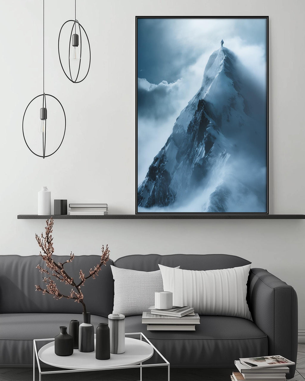 a large black and white photograph of a mountain peak, hanging on a wall above a gray couch with white pillows. The photograph appears to be a collage of multiple images, creating a striking visual contrast between the dark mountain and the lighter background.