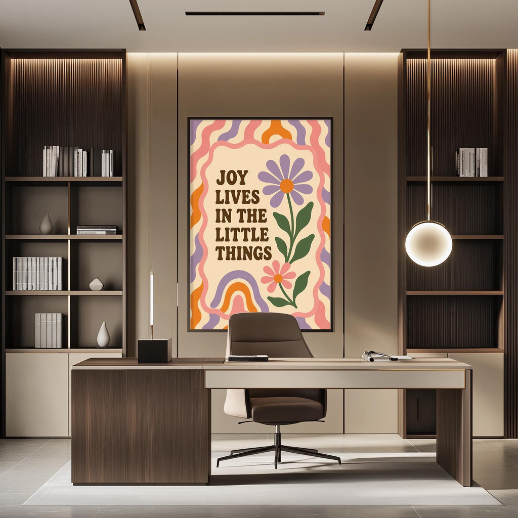 a modern office space with a large framed poster on the wall that reads "Joy lives in the little things". The office has a wooden desk, a chair, and a bookshelf filled with books. The overall design and decor create a calm and inspiring atmosphere.