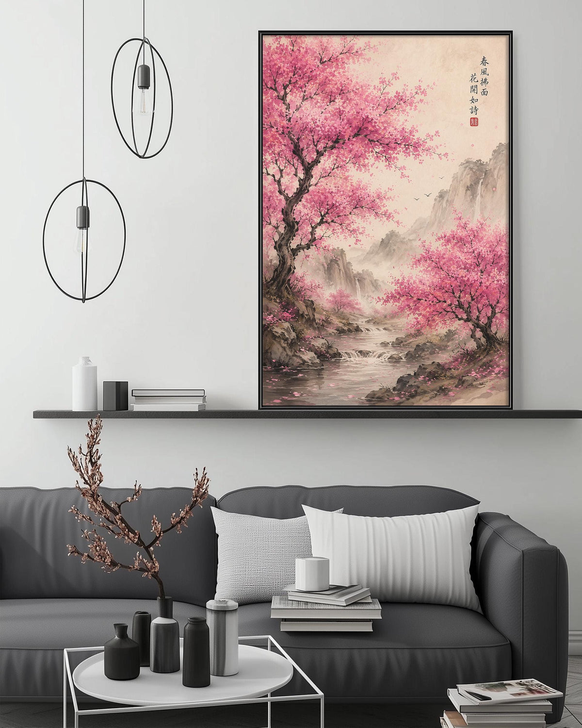 a large, framed painting of a serene landscape with pink cherry blossoms, hanging above a gray couch in a modern living room setting.