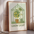 A framed poster with a green greenhouse and a lemon tree inside, along with the text "GROW LIGHT" below the illustration.
