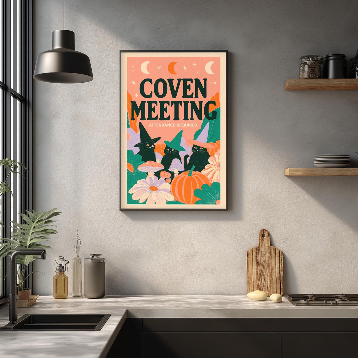 a kitchen counter with a framed poster of a witch and cat illustration hanging on the wall above it.