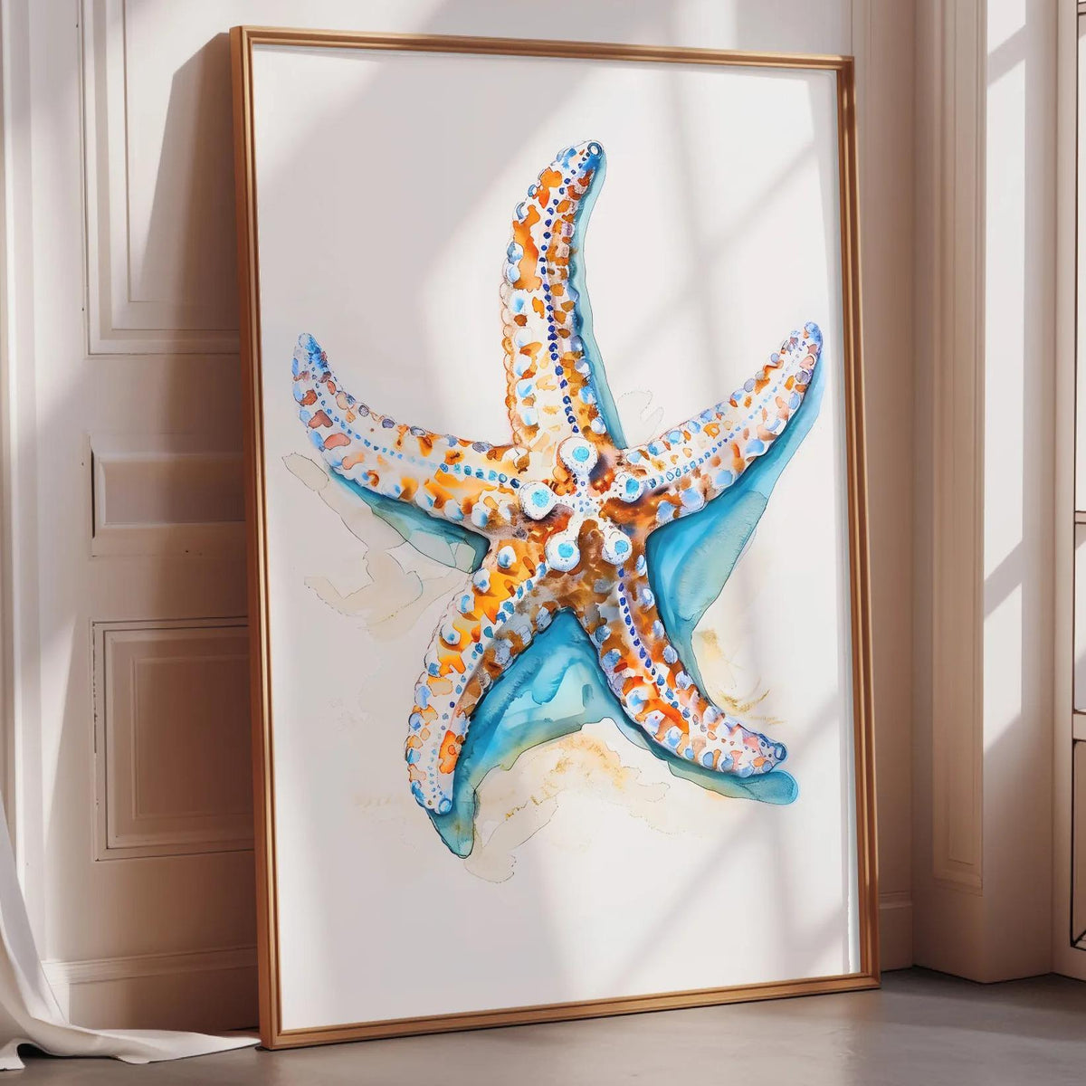 A framed watercolor painting of a starfish is displayed on a wall in a room with sunlight streaming in from a window.