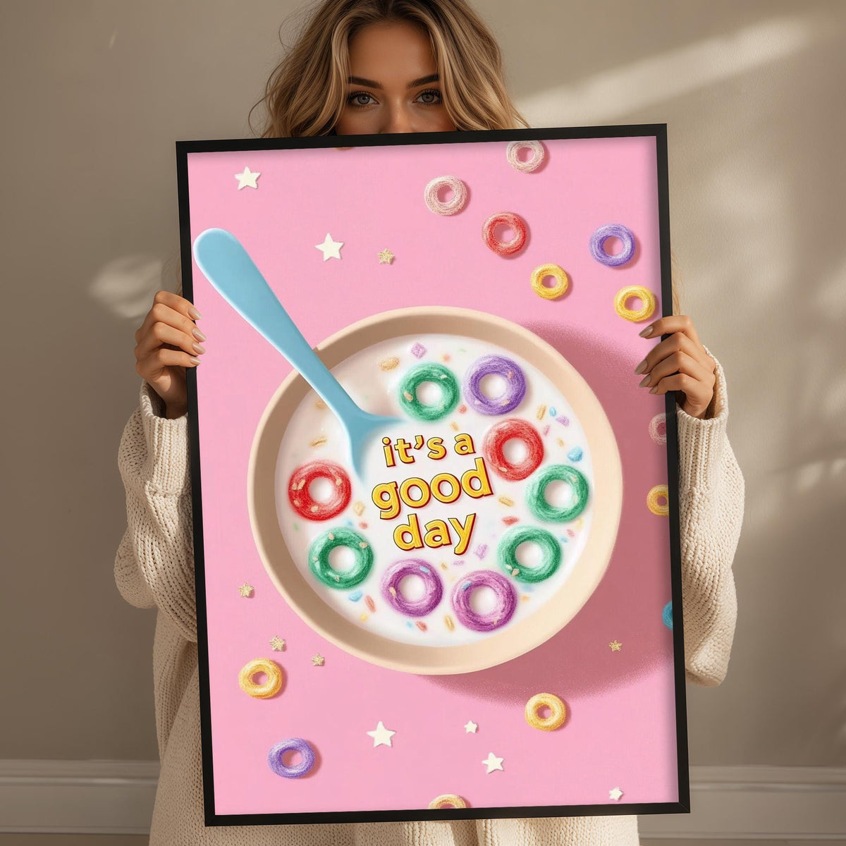 A woman holding a framed poster with a cereal bowl and colorful donuts on it, along with the text "it's a good day".