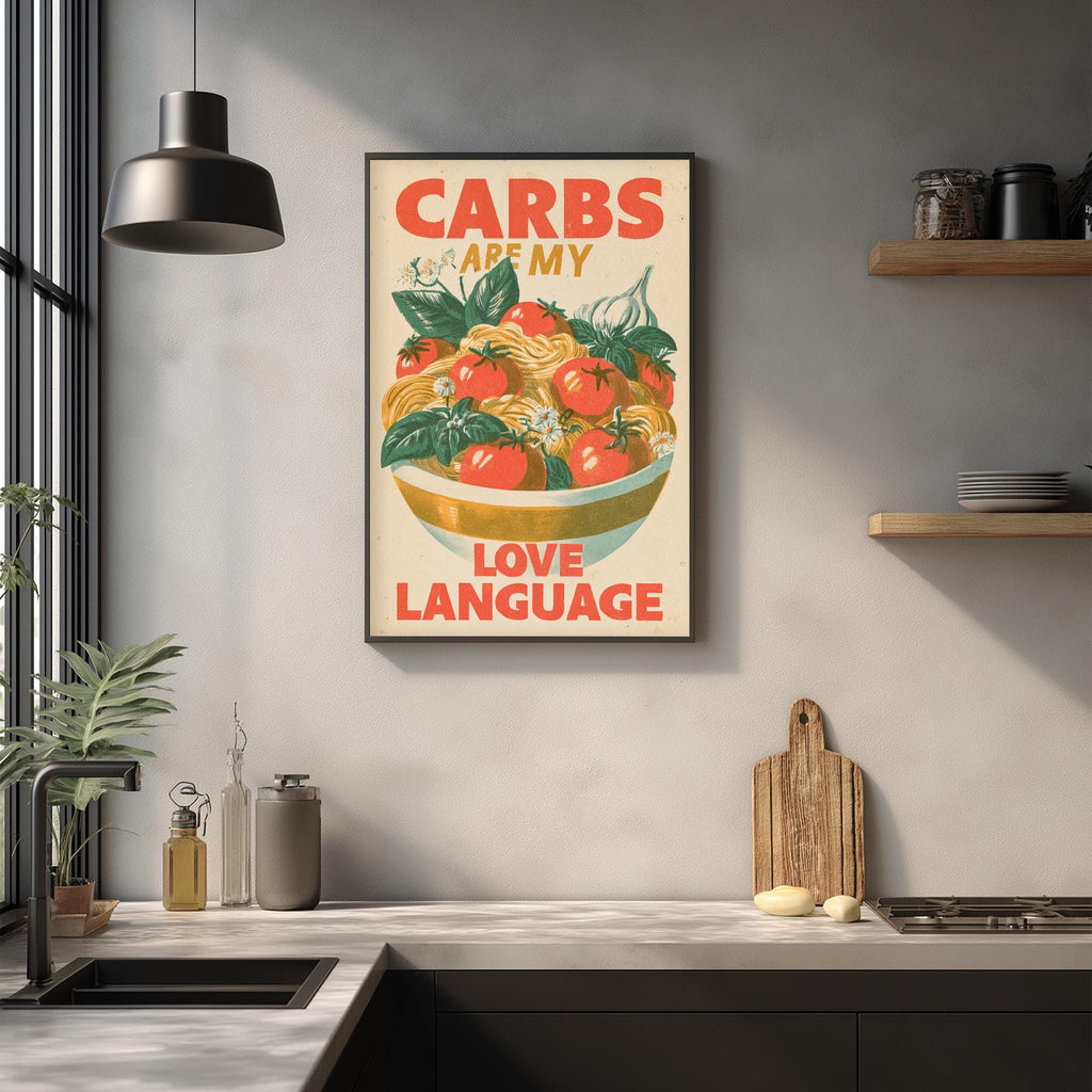 a kitchen counter with various kitchen items, including a bowl of fresh vegetables, a cutting board, and a sink. Above the counter, there is a framed poster with the text "CARBS ARE MY LOVE LANGUAGE" and an illustration of a bowl of vegetables.