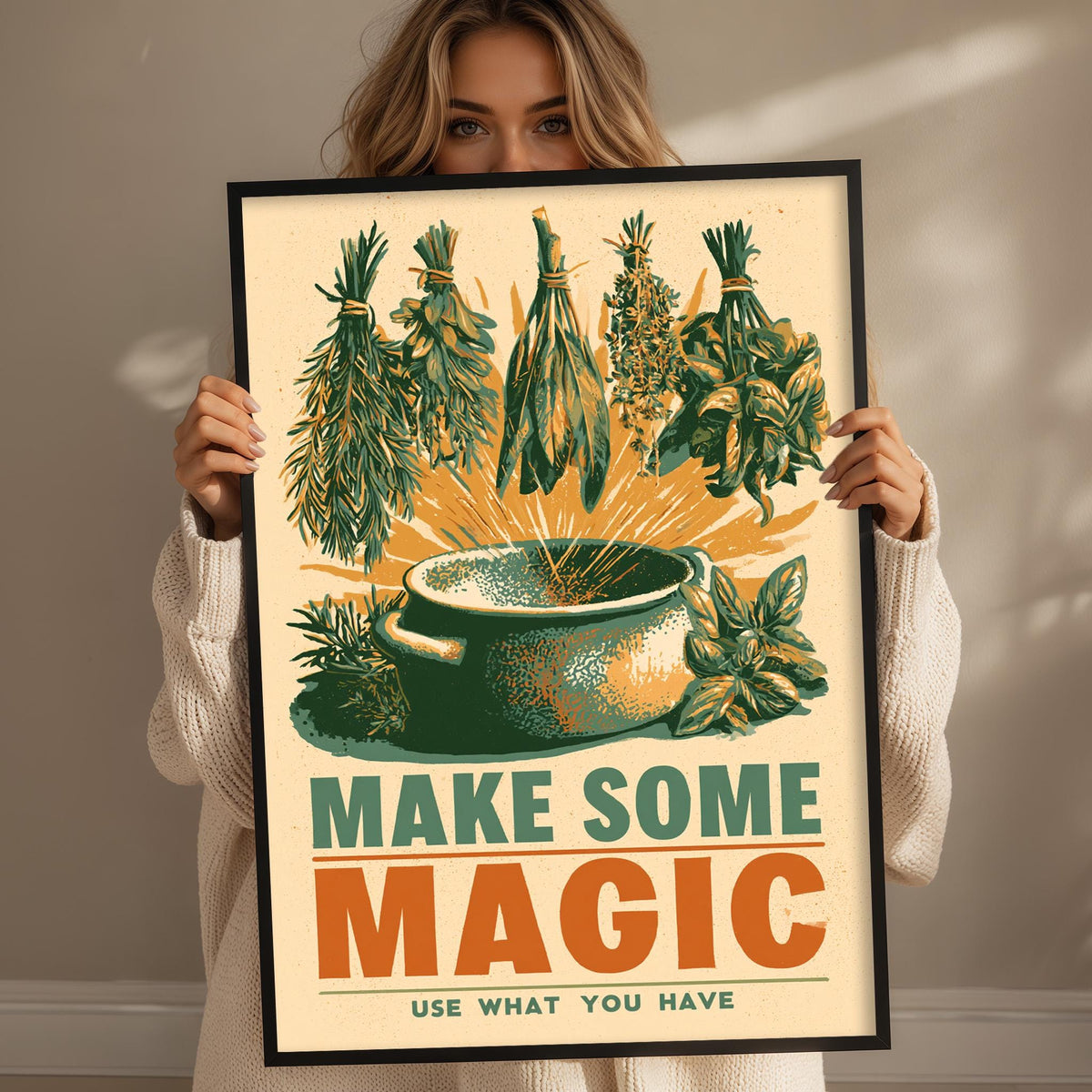 A woman holding a framed poster with a colorful illustration of herbs and a pot, along with the text "MAKE SOME MAGIC USE WHAT YOU HAVE".