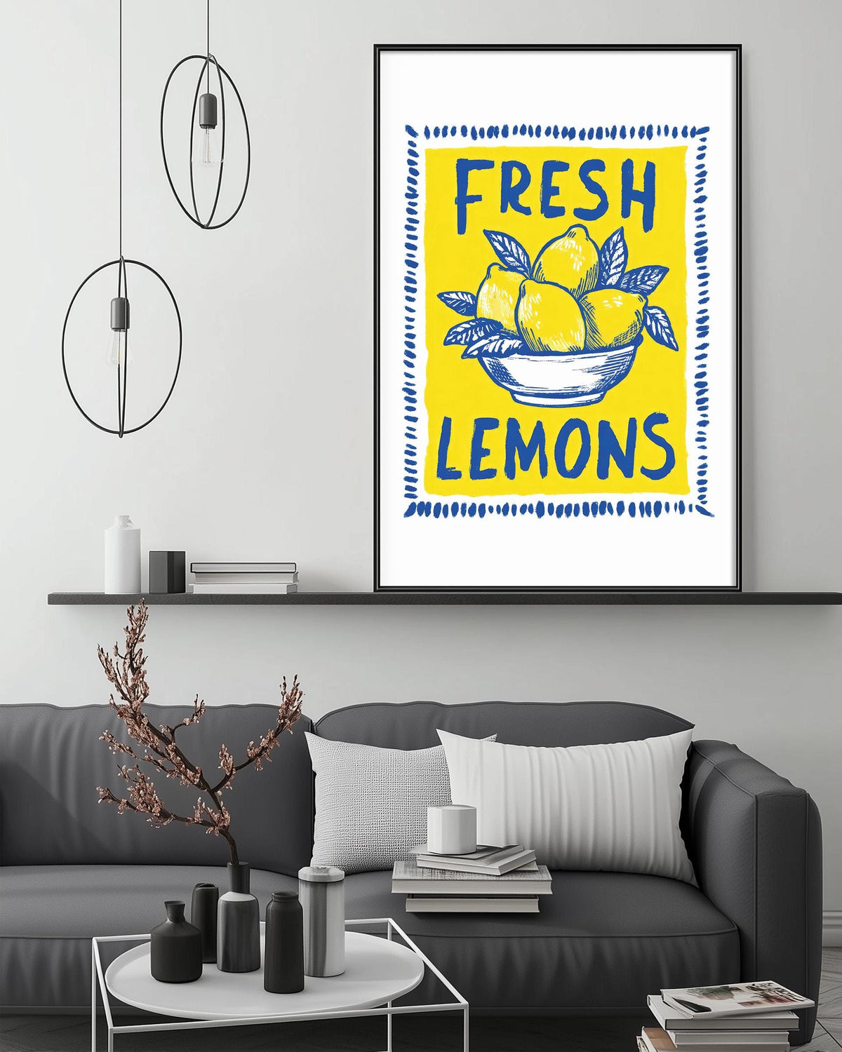 a living room with a gray couch, a coffee table, and a framed poster of lemons hanging on the wall.