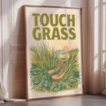 a framed poster with a vibrant illustration of a pair of hiking boots nestled in a field of tall grass, with a sun-like design in the background.