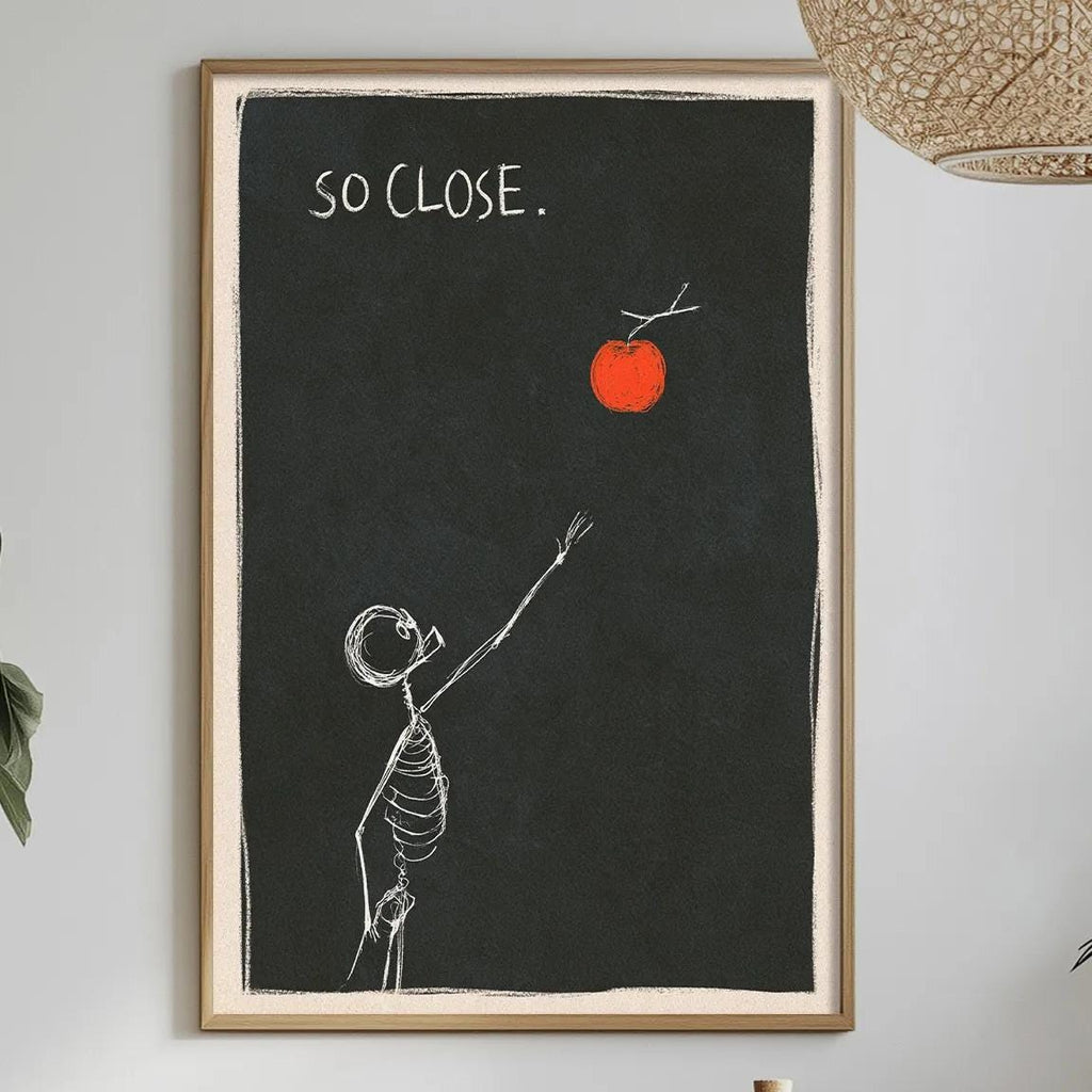 a dining table with a white tablecloth, a bowl of fruit, a bottle, and a vase with flowers. Above the table, there is a framed drawing of a skeleton reaching for an orange, with the text "SO CLOSE."