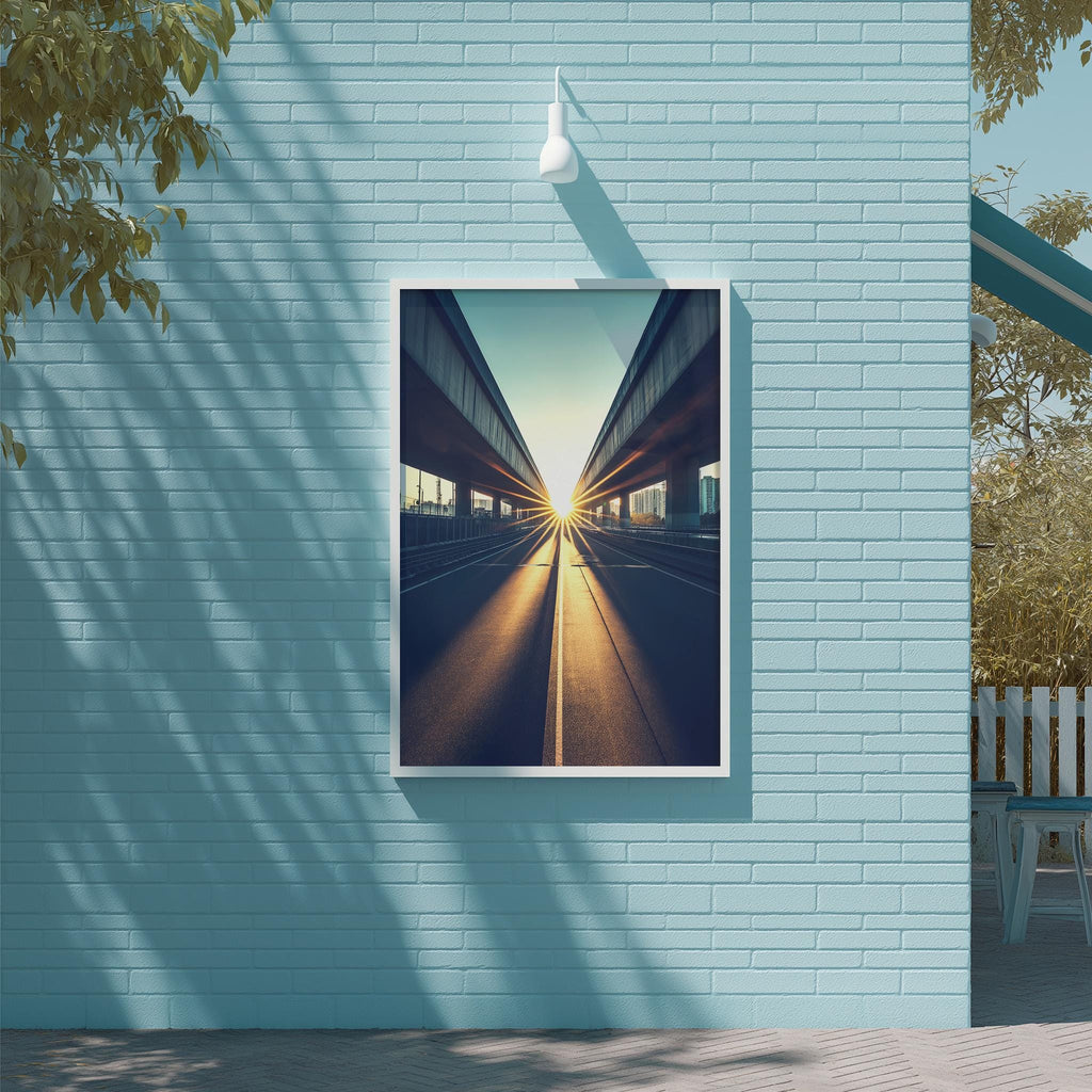 a large framed picture of a city street with a sunlit sky, hanging on a light blue brick wall.
