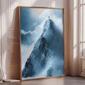 a large, framed picture of a mountain peak with a lone person standing on top, overlooking the snowy landscape below.